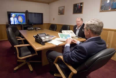  President George W. Bush is handed a map by Deputy Chief of Staff Joe Hagin, center, during a video teleconference with federal and state emergency management organizations on Hurricane Katrina from his Crawford, Texas ranch on Sunday August 28, 2005.